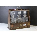 Oak and Brass Mounted Tantalus with three matching decanters, with key, 34cms wide x 29.5cms high