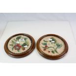 A pair of circular framed and glazed wool work tapestries of flowers.