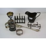 A collection of fully hallmarked sterling silver items to include a toast rack, milk jug, napkin