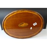 An early 20th century oval mahogany tray with scalloped edge and inlaid shell decoration to centre.