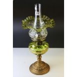 An antique French oil lamp with gilt metal base a green glass well with gilded floral decoration and