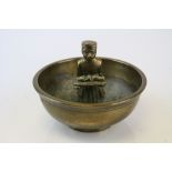 A vintage brass ashtray with central figure.