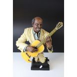 A 20th century resin figure of a blues guitarist on plinth.