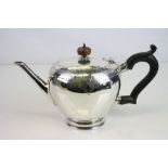 Silver teapot, melon-shaped form raised on foot, engraved mask and scroll decoration, ebony-type