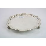 Early 20th century silver salver raised on three scroll feet, Chippendale border, engraved