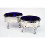 Pair of George III silver open oval salt cellars raised on three ball and claw feet, pierced urn and
