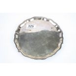 Silver salver raised on four scroll feet, pie crust border, plain polished form, makers Viners