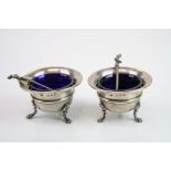 Pair of silver salt cellars, cauldron form raised on three feet, blue glass liners, makers