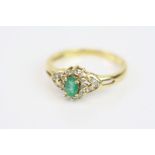 Emerald and diamond 18ct yellow gold cluster ring, the oval emerald with twelve small round