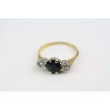 Sapphire and diamond three stone 18ct yellow gold ring, central blue-black sapphire with two small