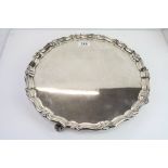 Large silver salver raised on four scroll feet, plain polished with cast shell and scroll border,