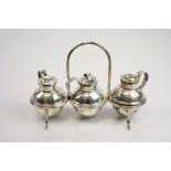 Three piece silver cruet and stand comprising salt, pepper and mustard pots, modelled as lidded