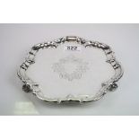Silver card tray raised on three scroll feet, engraved foliate decoration surround blank cartouche