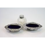 Pair of Edwardian silver oval open salt cellars, repoussé floral and scroll decoration, blue glass