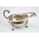 Edwardian silver sauce boat, raised on three hoof feet, scroll handle with cast acanthus leaf,