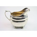 Silver milk jug raised on four bun feet, plain polished body, makers Harrods Ltd, London 1937,