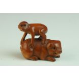 Japanese Carved Boxwood Netsuke in the form of a Monkey stood on a Pig, signed, 5cms long