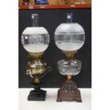 An antique early 20th century oil lamp with cast iron base clear glass well floral decorated shade