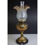 An antique brass and ceramic oil lamp with pinched body design with amber tipped shade and clear