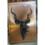 A copper effect plaque mounted with a sculpture of an Antelope.