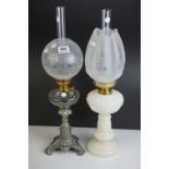 An antique opaque glass oil lamp with floral shade and chimney together with one other with metal