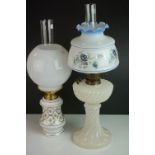 An antique oil lamp with opaque base and floral decorated shade and chimney together with one