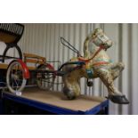 A mid 20th century pedal toy horse and trap with rubber wheels.