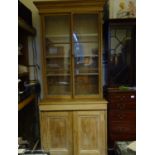 Pine bookcase with twin glazed top section 5'6 tall, base section containing 2 cupboards, 1 door
