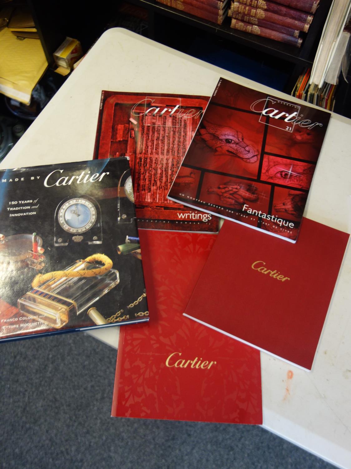 13 x Vintage Cartier magazine or programmes and 1 copy of Cologni made by Cartier hard backed book