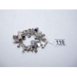 Silver charm bracelet with numerous silver charms, 121 grams
