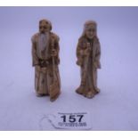 Pair of Japanese Okimono figurines, both holding staffs, each one signed to the base, both depicting