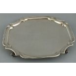 A square silver salver, Sheffield 1929, Eric Viner, with re-entrant corners, and raised on scroll