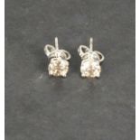 A pair of 18ct white gold round brilliant cut four claw diamond studs, 1.11ct total