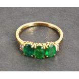 A three stone emerald and diamond ring, the oval cut stones totalling approx. 2.20ct set between