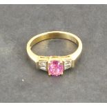 A pink sapphire and diamond dress ring, the central stone flanked by baguette cut diamonds, with a