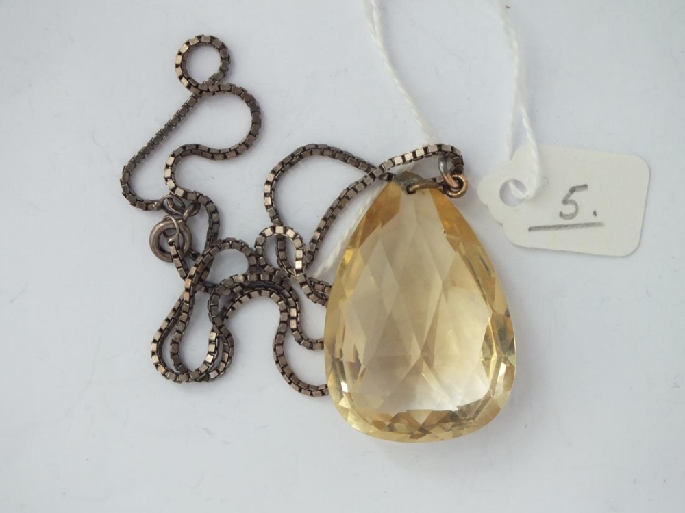 A citrine coloured pendant on a silver neck chain