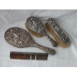 A heavy Eastern silver dressing table set of hand mirror, two brushes and a comb with chased