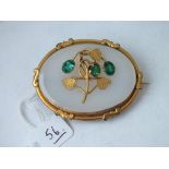 A Victorian oval gold and onyx mounted brooch, mounted with three green stones