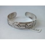 A silver torque bangle with rural scenes