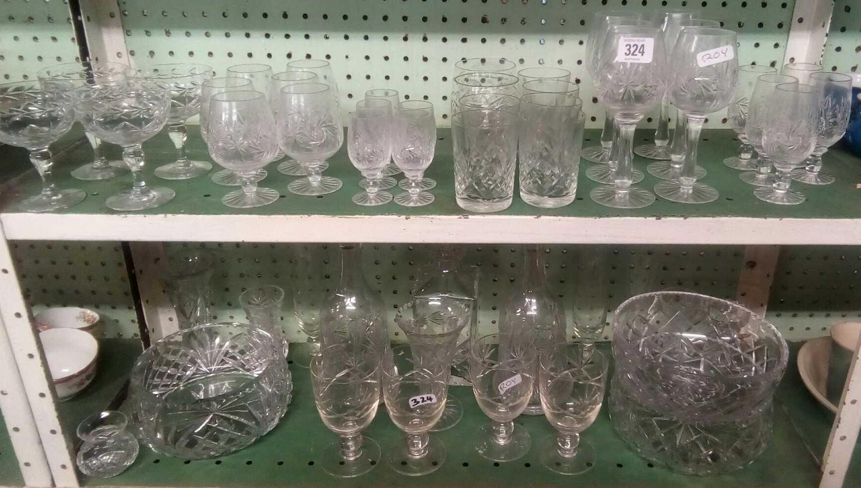 TWO SHELVES OF CUT GLASS DECANTERS, FRUIT BOWLS, WINE GLASSES ETC