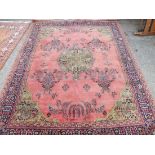A pink ground oriental carpet with blue border - 9'6" x 8'