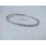 A white gold bangle, hinged and set with stones in 9ct - 4.4gms