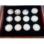 A boxed set of 12 Queen Mother boxed silver coins with paperwork.