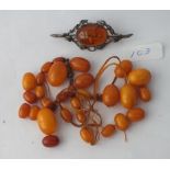 A silver amber brooch & assorted amber beads