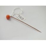 A coral mounted stick pin set in gold