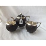 An unusual three-piece coconut-mounted tea set with carved panels of figures