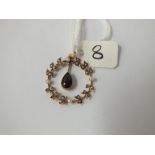 An attractive circular pearl pendant with central garnet drop in 9ct