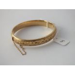 A good engraved gold hinged bangle in 9 ct - 11.4gms