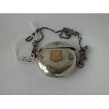 A circular silver vesta case with 9ct overlaid shield on chain