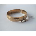 AN ENGRAVED HINGED BANGLE IN 9CT - 16.gms